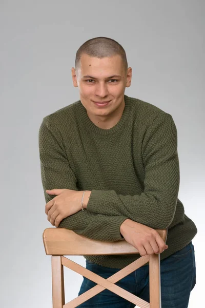 A young man is skinhead in a green military style sweater. studio. — Stock Photo, Image