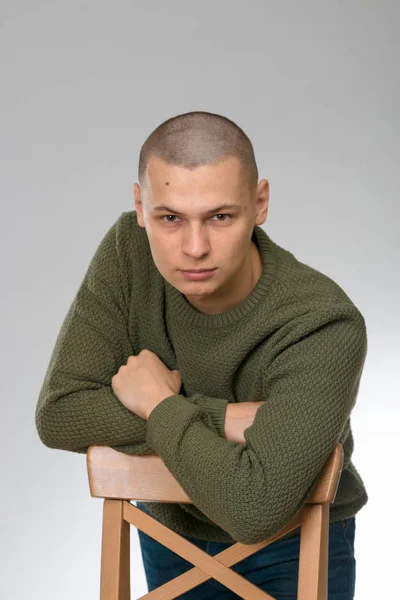 Un jeune homme est skinhead dans un pull vert de style militaire. studio . — Photo