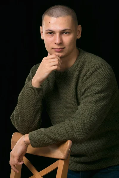 A young man is skinhead in a green military style sweater. studio. — Stock Photo, Image