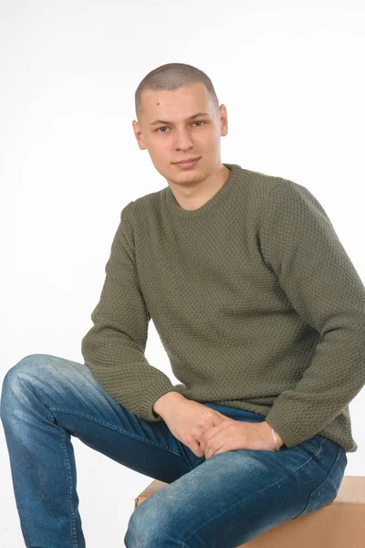 A young man is skinhead in a green military style sweater. studio. — Stock Photo, Image