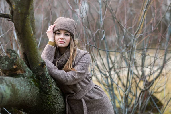 Dívka v pletené čepici a šálu v padlý strom na podzim na povaze. — Stock fotografie