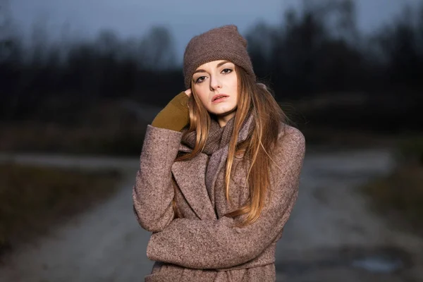 Chica en un sombrero de punto y bufanda se congela en la noche en el otoño en la naturaleza . — Foto de Stock