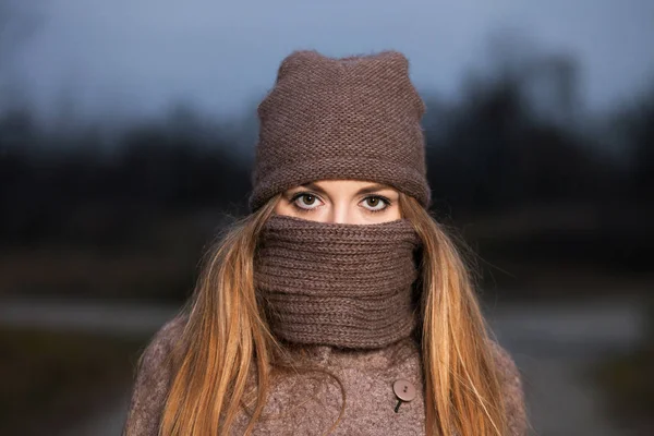 Menina em um chapéu de malha e cachecol congela à noite no outono na natureza . — Fotografia de Stock