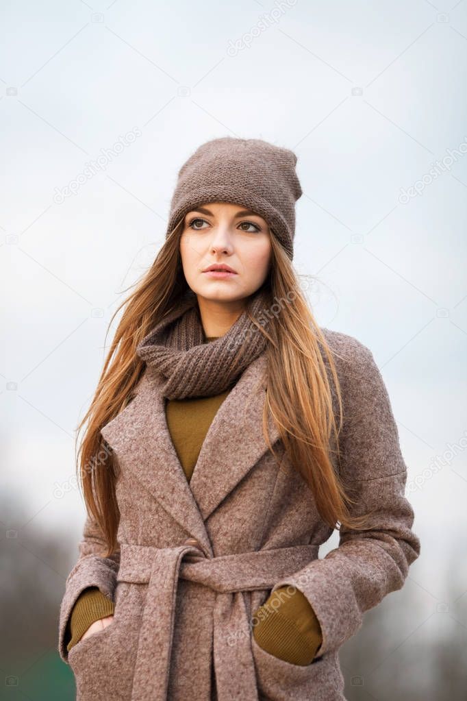 girl in a knitted cap and scarf in the autumn on nature. cold.