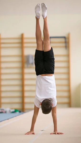 A fiatalember hajt végre gimnasztikai gyakorlatokat az edzőteremben. — Stock Fotó