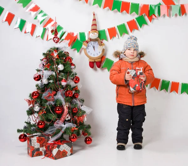 Ragazzo vicino a un albero di Natale su uno sfondo bianco . — Foto Stock