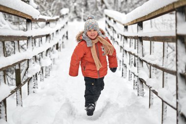 neşeli çocuk kışın köprü üzerinde çalışır..