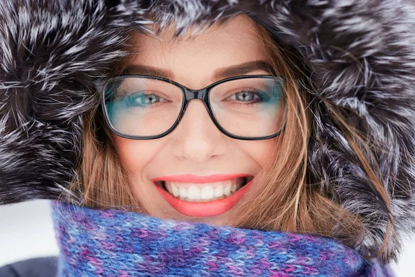 A large portrait of a girl wearing glasses in a fur hood in winter. — Stock Photo, Image