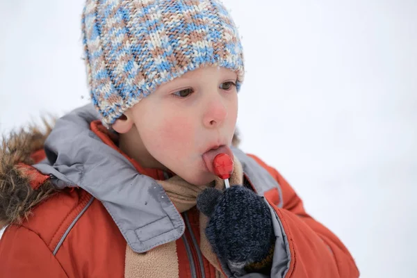 Niño en un sombrero de invierno de punto con caramelos de caramelo . — Foto de Stock