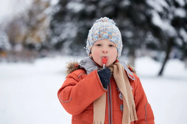 Niño en un sombrero de invierno de punto con caramelos de caramelo . — Foto de Stock