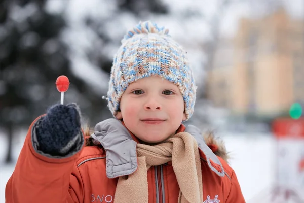 Jongen in een winter gebreide muts met candy candy. — Stockfoto
