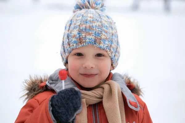 Niño en un sombrero de invierno de punto con caramelos de caramelo . — Foto de Stock