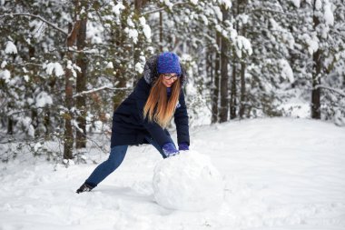 Kış eğlence. örgü şapkalı kız bir kardan adam sculpts.