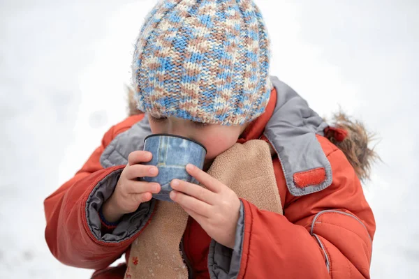 Niño bebe té de una taza en la helada . — Foto de Stock