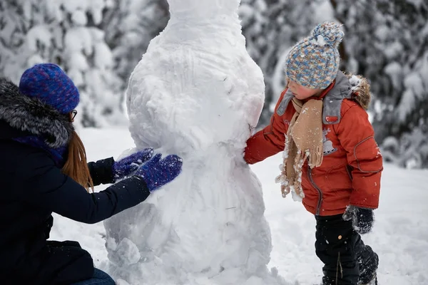 Зимові забави. дівчинка і хлопчик роблять сніжки . — стокове фото