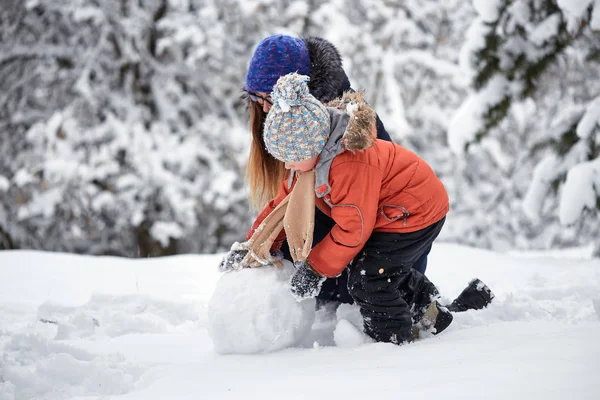 Diversión invernal. una chica y un chico haciendo bolas de nieve . — Foto de Stock