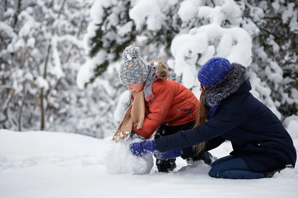 Diversión invernal. una chica y un chico haciendo bolas de nieve . — Foto de Stock