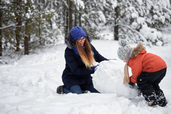 Diversión invernal. una chica y un chico haciendo bolas de nieve . — Foto de Stock