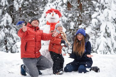 Kış eğlence. bir kız, bir adam ve bir çocuk bir kardan adam yapma.