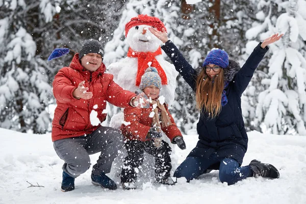 Зимові забави. дівчинка, чоловік і хлопчик роблять сніговика . — стокове фото