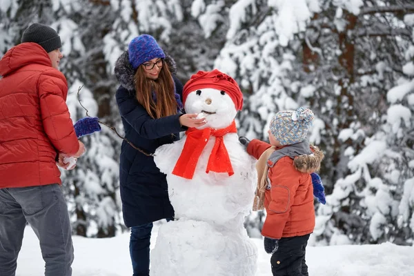 Зимнее веселье. девочка, мужчина и мальчик делают снеговика . — стоковое фото