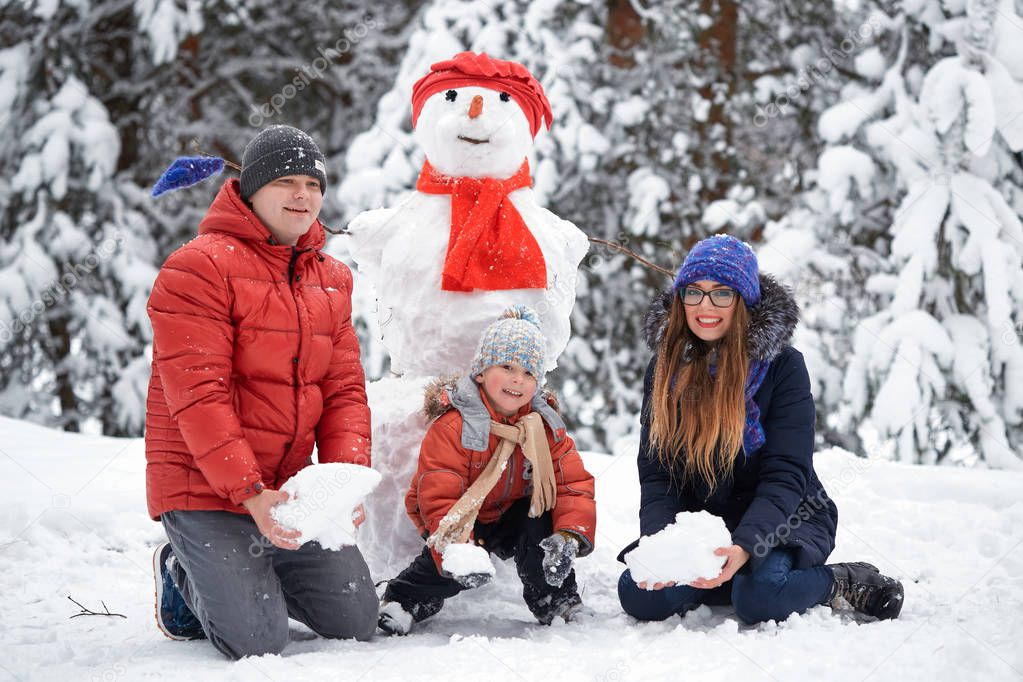 winter fun. a girl, a man and a boy making a snowman.
