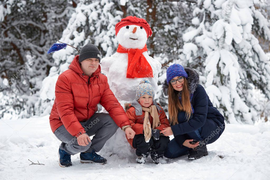 winter fun. a girl, a man and a boy making a snowman.