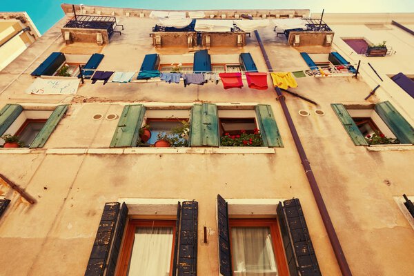 Venice, Italy - August 14, 2017: windows of a multistory residential building with clothesline ropes