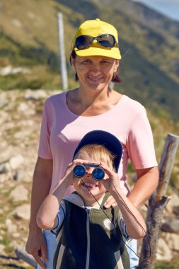 Anne ve oğlu turist dağlarda dürbünlü.