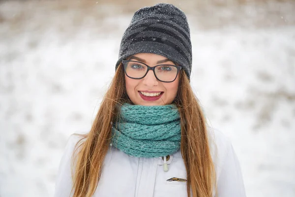 Porträt eines fröhlichen Mädchens mit Brille im Schneefall im Winter. — Stockfoto