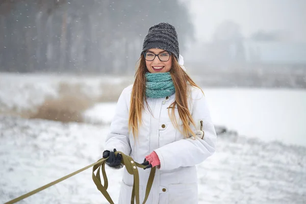 Portrait of a cheerful girl with glasses in a snowfall in winter. — Stock Photo, Image
