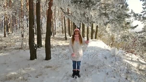 美丽的女孩在一个粉红色的帽子和手套在冬天的雪林 — 图库视频影像