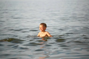 Çocuk denizde yüzüyor.