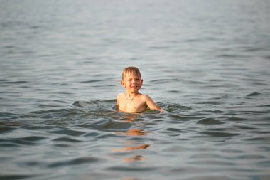 Çocuk denizde yüzüyor.