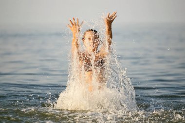 Su ile sprey. Eğleniyor kız denizde Yüzme.