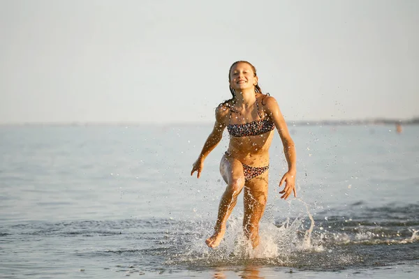 Diversão de água. a menina corre ao longo da costa . — Fotografia de Stock