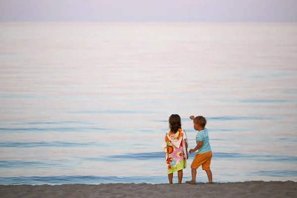 Crianças menino e menina romance na praia colorido pôr do sol . — Fotografia de Stock