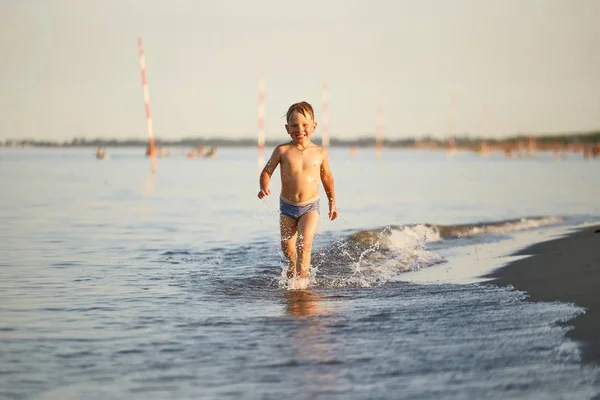 Diversão de água. o menino corre ao longo da praia — Fotografia de Stock