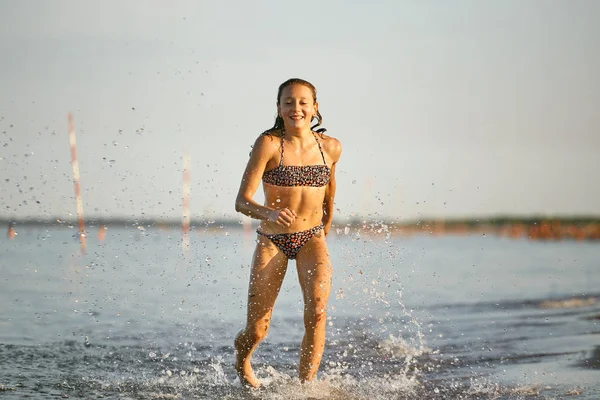 Diversão de água. a menina corre ao longo da costa . — Fotografia de Stock