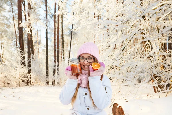 Κορίτσι σε ένα ροζ καπέλο πίνοντας ζεστό κρασί το χειμώνα στο δάσος. — Φωτογραφία Αρχείου