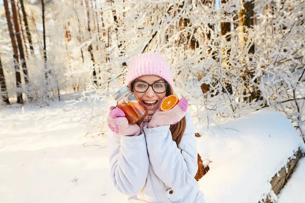Κορίτσι σε ένα ροζ καπέλο πίνοντας ζεστό κρασί το χειμώνα στο δάσος. — Φωτογραφία Αρχείου