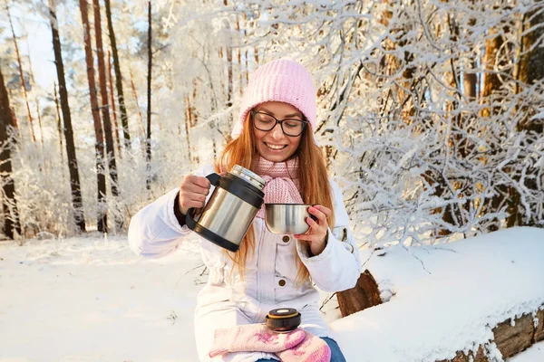 Κορίτσι σε ένα ροζ καπέλο με ένα θερμός το χειμώνα στο δάσος. — Φωτογραφία Αρχείου