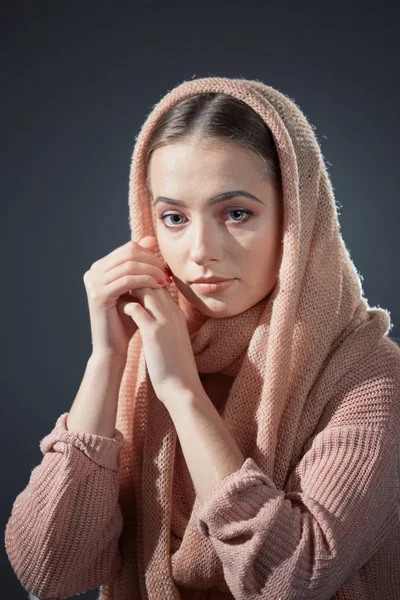 Stora känslomässiga porträtt av en vacker flicka i stickad rosa huvudduk i studion på en grå bakgrund. — Stockfoto