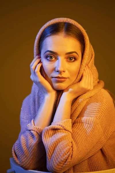 Gran retrato emocional de una hermosa chica en un pañuelo rosa de punto en el estudio sobre un fondo gris . — Foto de Stock