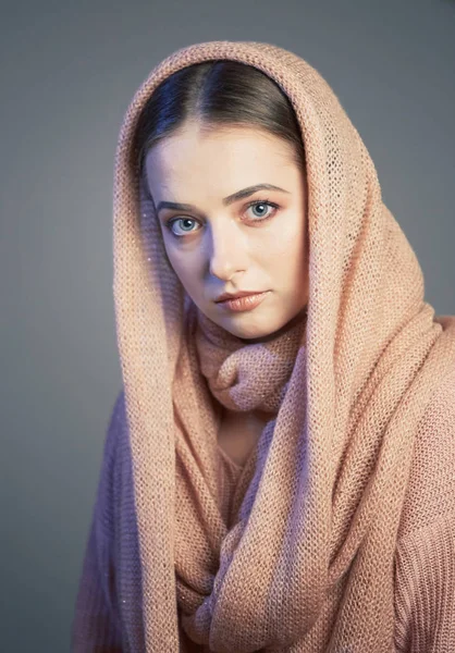 Gran retrato emocional de una hermosa chica en un pañuelo rosa de punto en el estudio sobre un fondo gris . —  Fotos de Stock