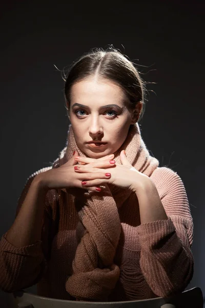 Mooi meisje in roze gebreide trui. emotionele portret op een donkere achtergrond. — Stockfoto