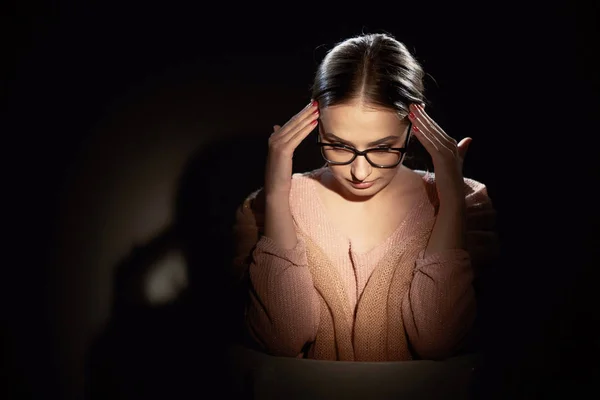 Meisje in glazen in studio op een donkere achtergrond. lichte vlekken. — Stockfoto