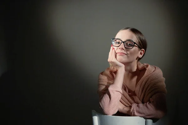 Girl in glasses in studio on a dark background. light spots. — Stock Photo, Image