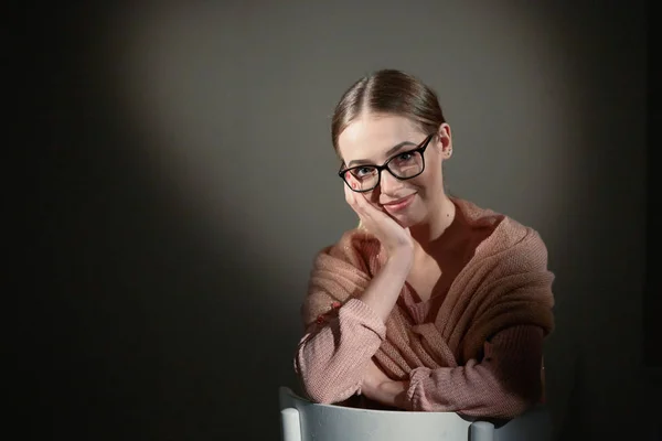 Chica en gafas en el estudio sobre un fondo oscuro. manchas de luz . — Foto de Stock