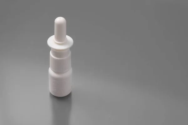 Termómetro médico con tabletas y un spray para la nariz sobre un fondo gris en el estudio . — Foto de Stock